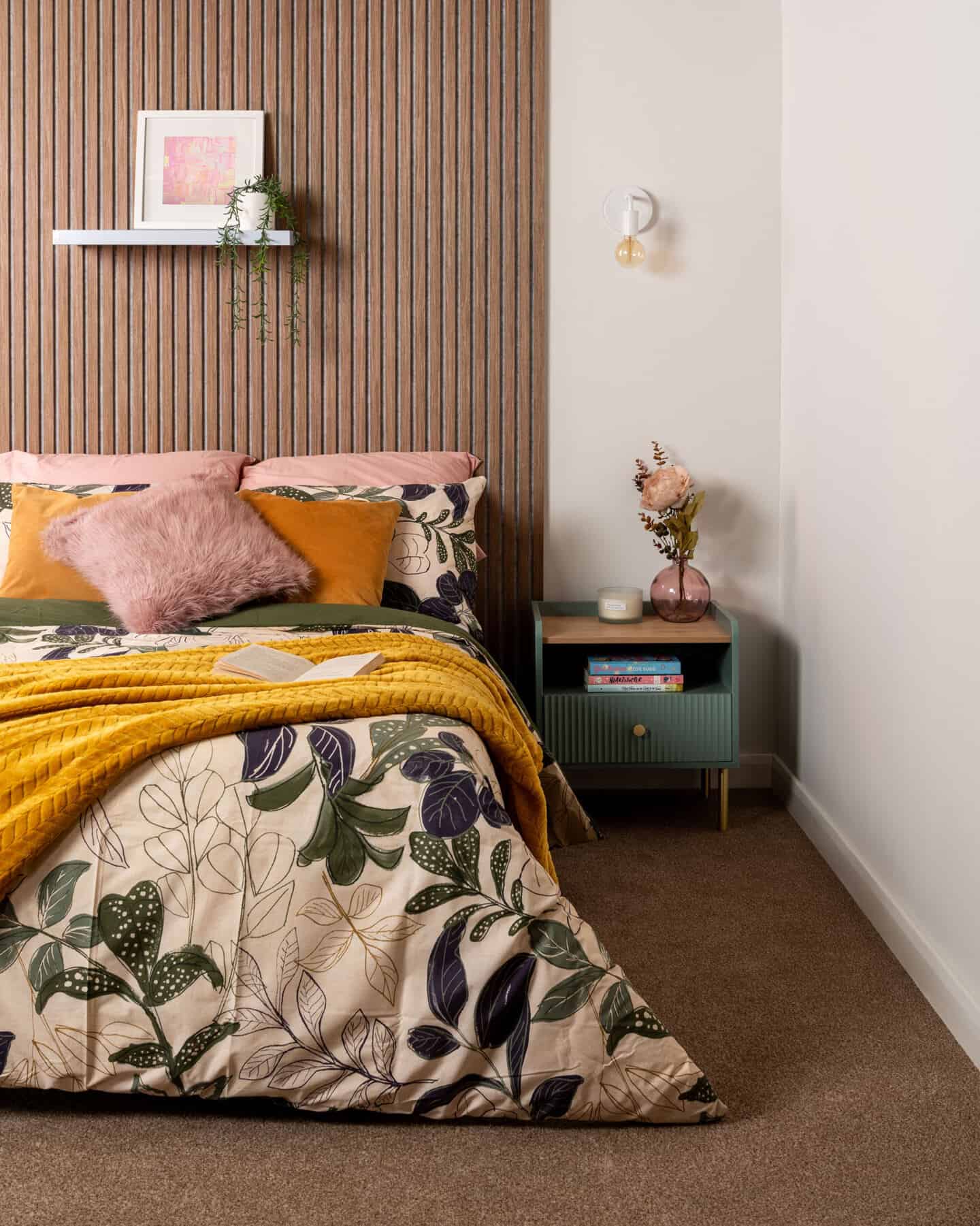 wooden slat wall behind a bed covered in botanical bedding