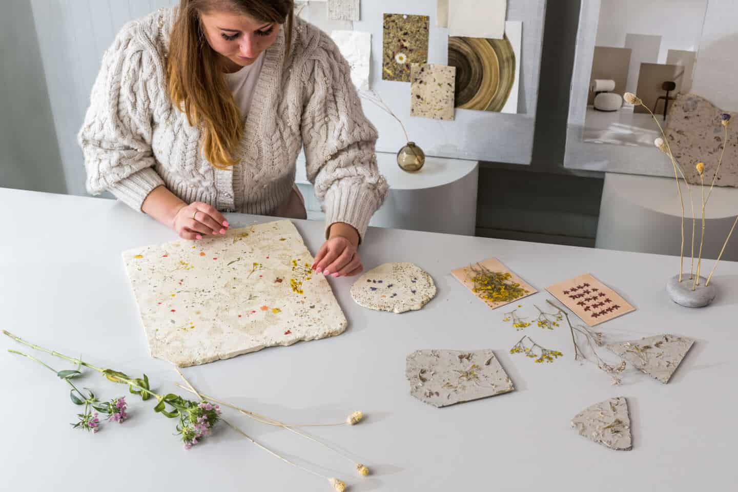 Anastasiia Kudashova, Chief Designer at Quick-Step. There are wildflowers on her desk and prototypes of concrete with wild flowers embedded in it.