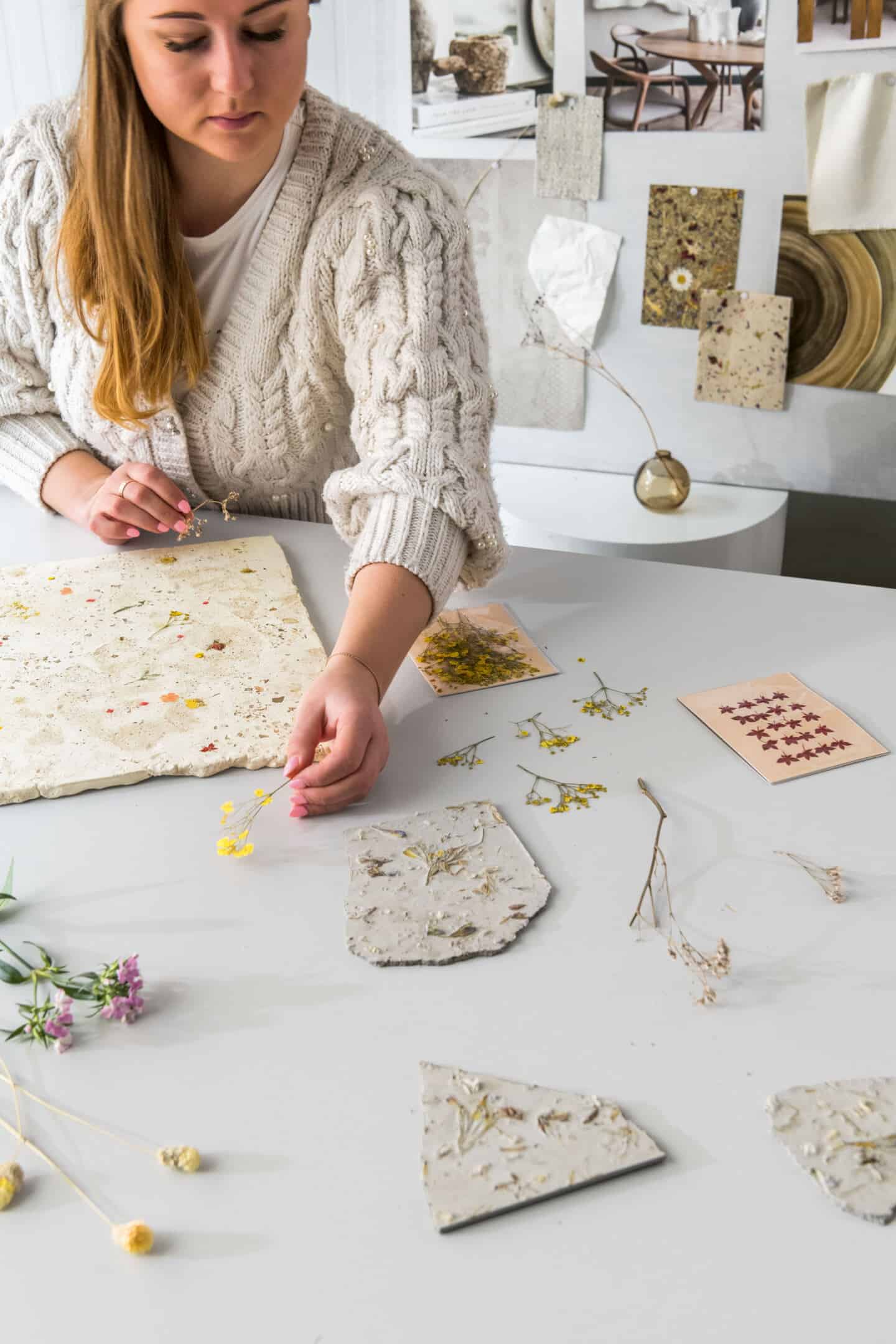 Anastasiia Kudashova, Chief Designer at Quick-Step. There are wildflowers on her desk and prototypes of concrete with wild flowers embedded in it.