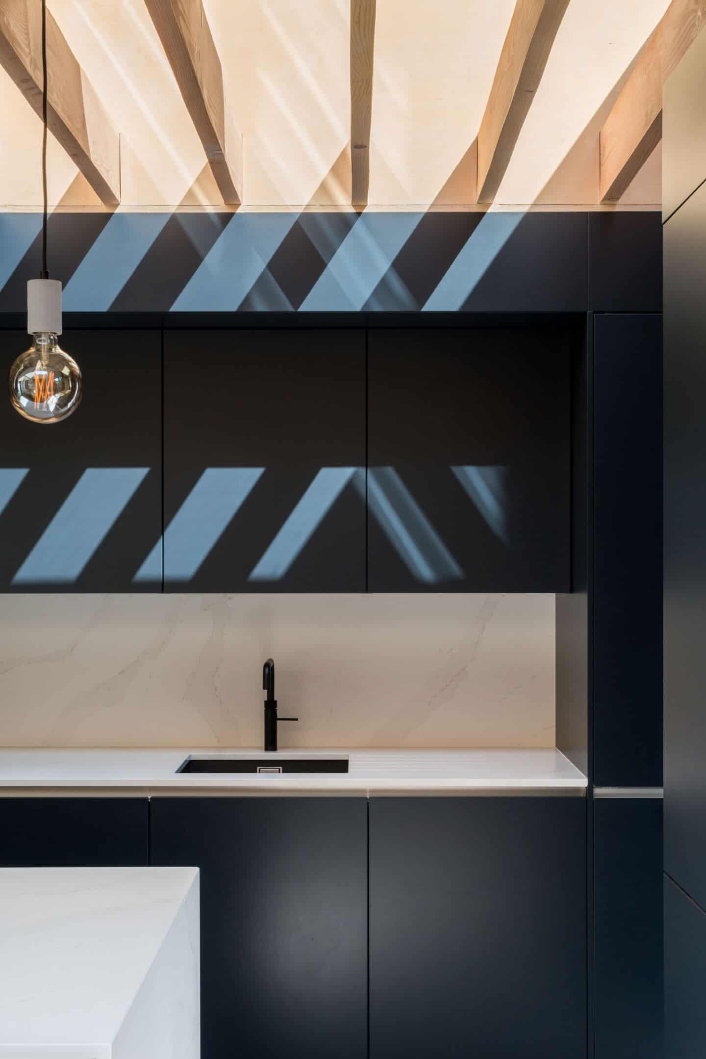 Shadows cast across kitchen cabinets as natural light floods in from roof lights