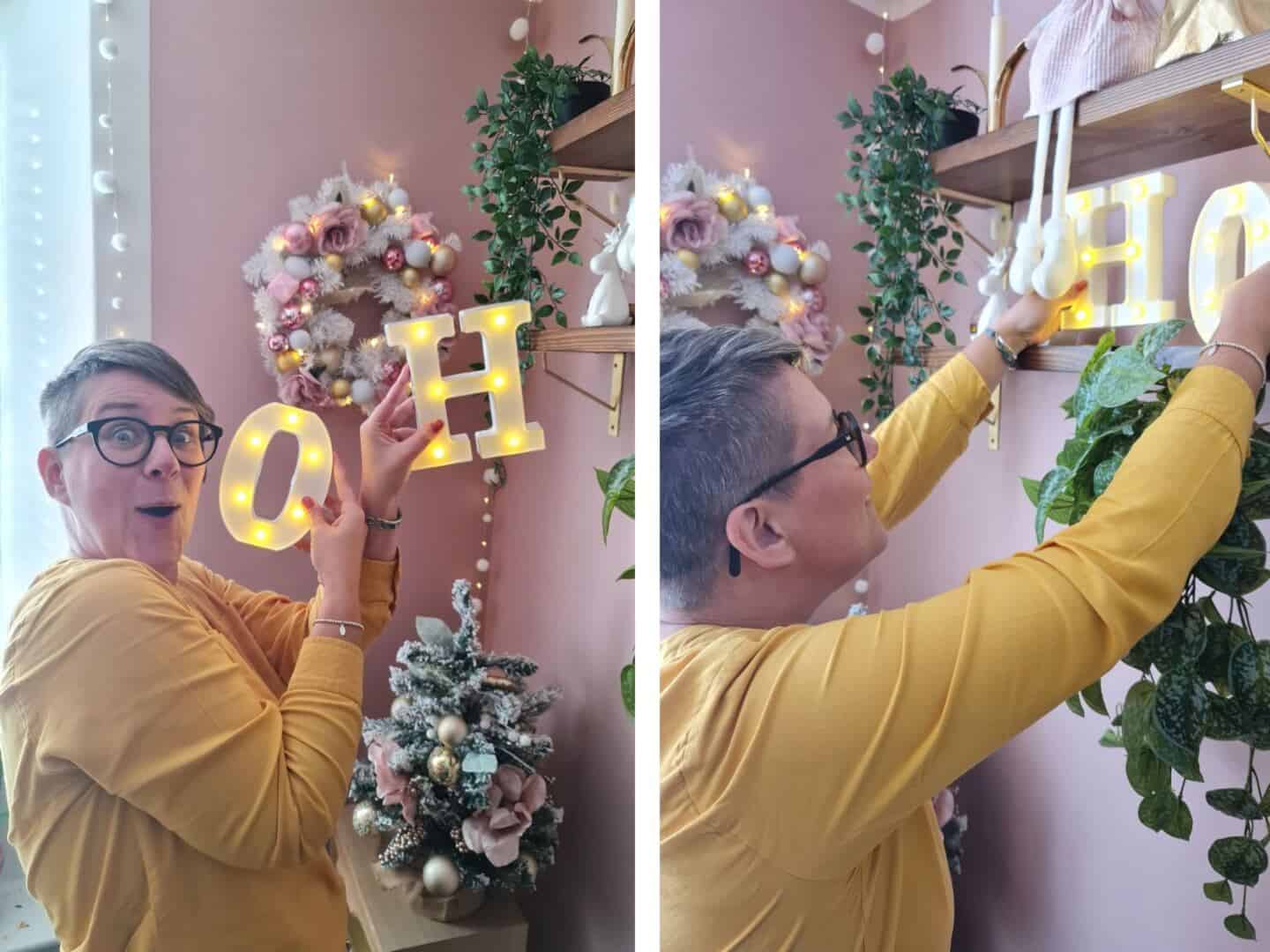 A woman placing light up letters saying Ho Ho Ho on a shelf in a pink home office