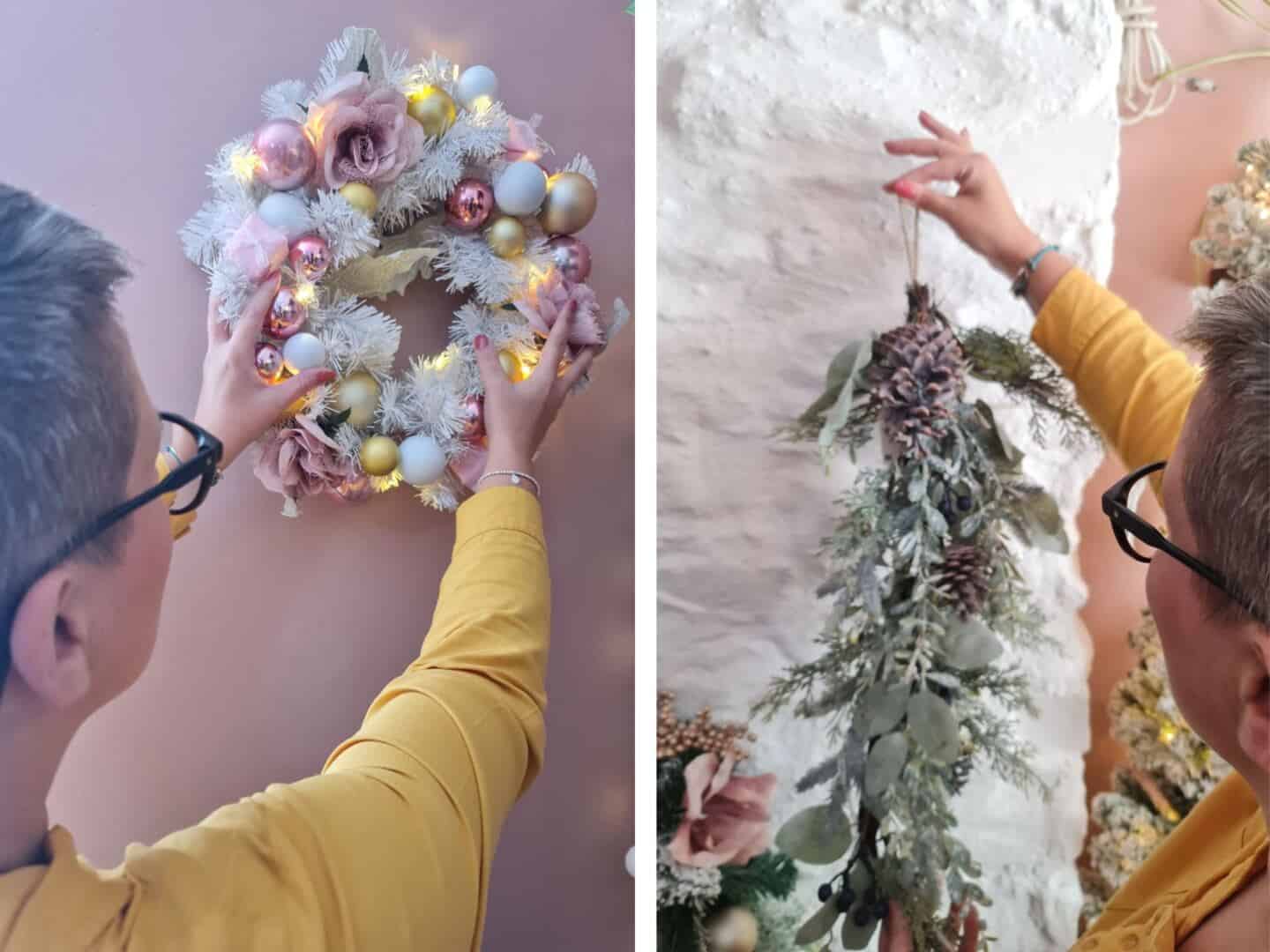 A woman places Christmas wreaths on the wall in a pink home office