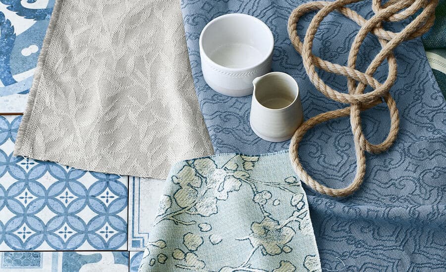 Aylin fabric by Villa Nova in shades of blue laid out on top of some blue tiles