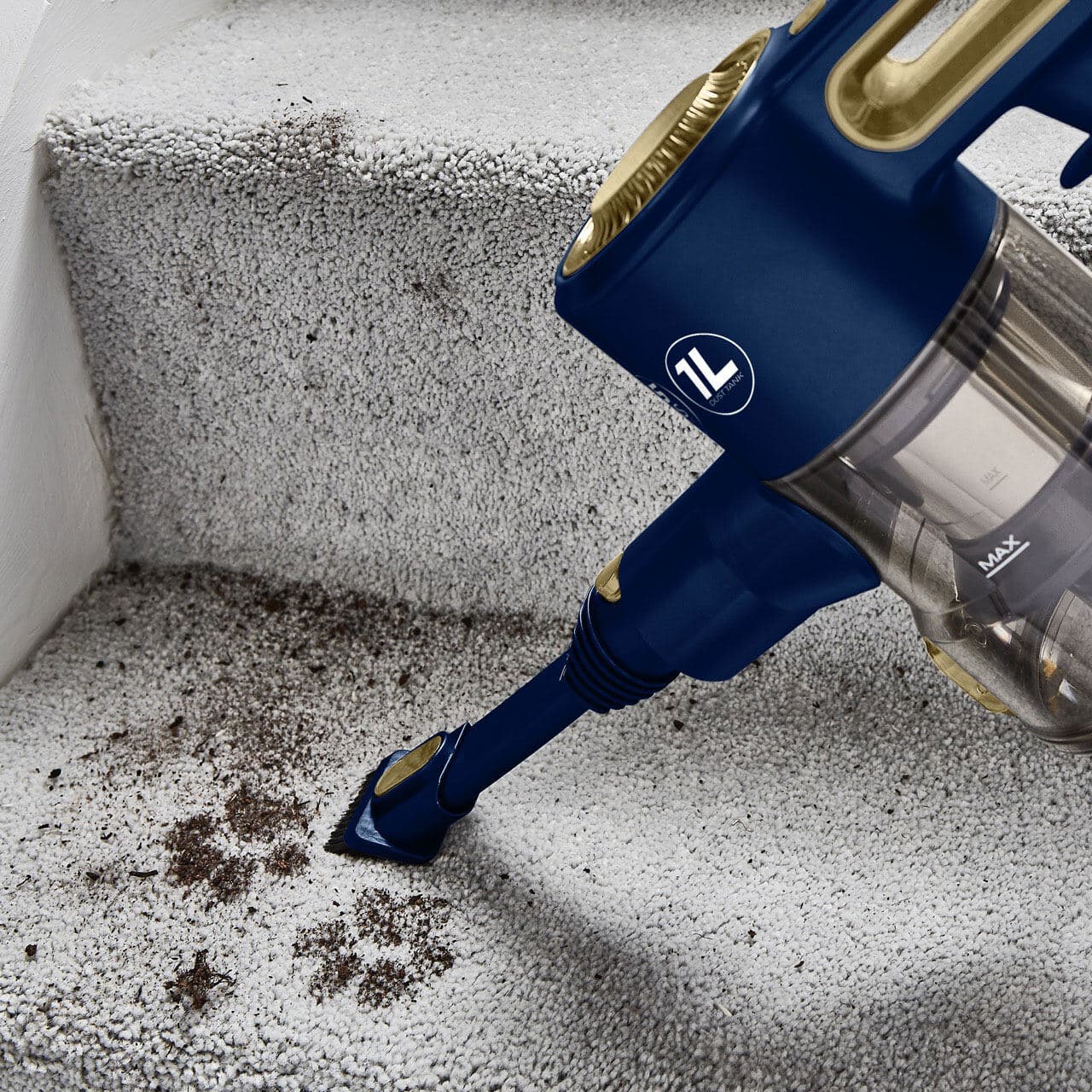 A hand-held vacuum cleaner hoovers up muddy dog paw marks on a grey carpet