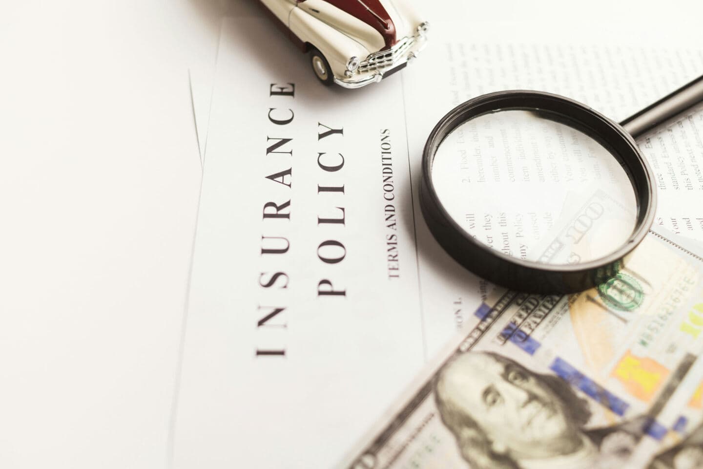 papers entitled Insurance policy spread on a desk with a magnifying glass on top 