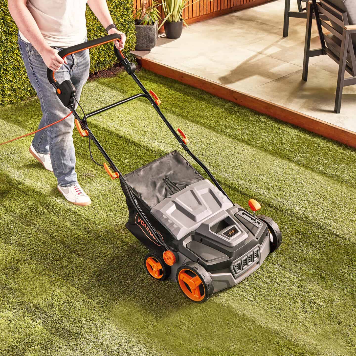 A man pushing an artificial grass brush across artificial grass. The brush looks just like a lawn mower 