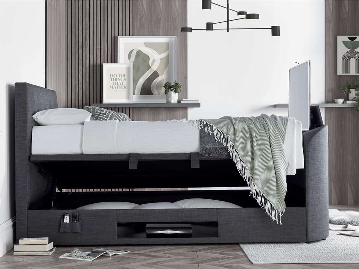 A bedroom with wood panelling in the walls. It features a grey side-opening linen ottoman bed with integrated TV in the footer. 