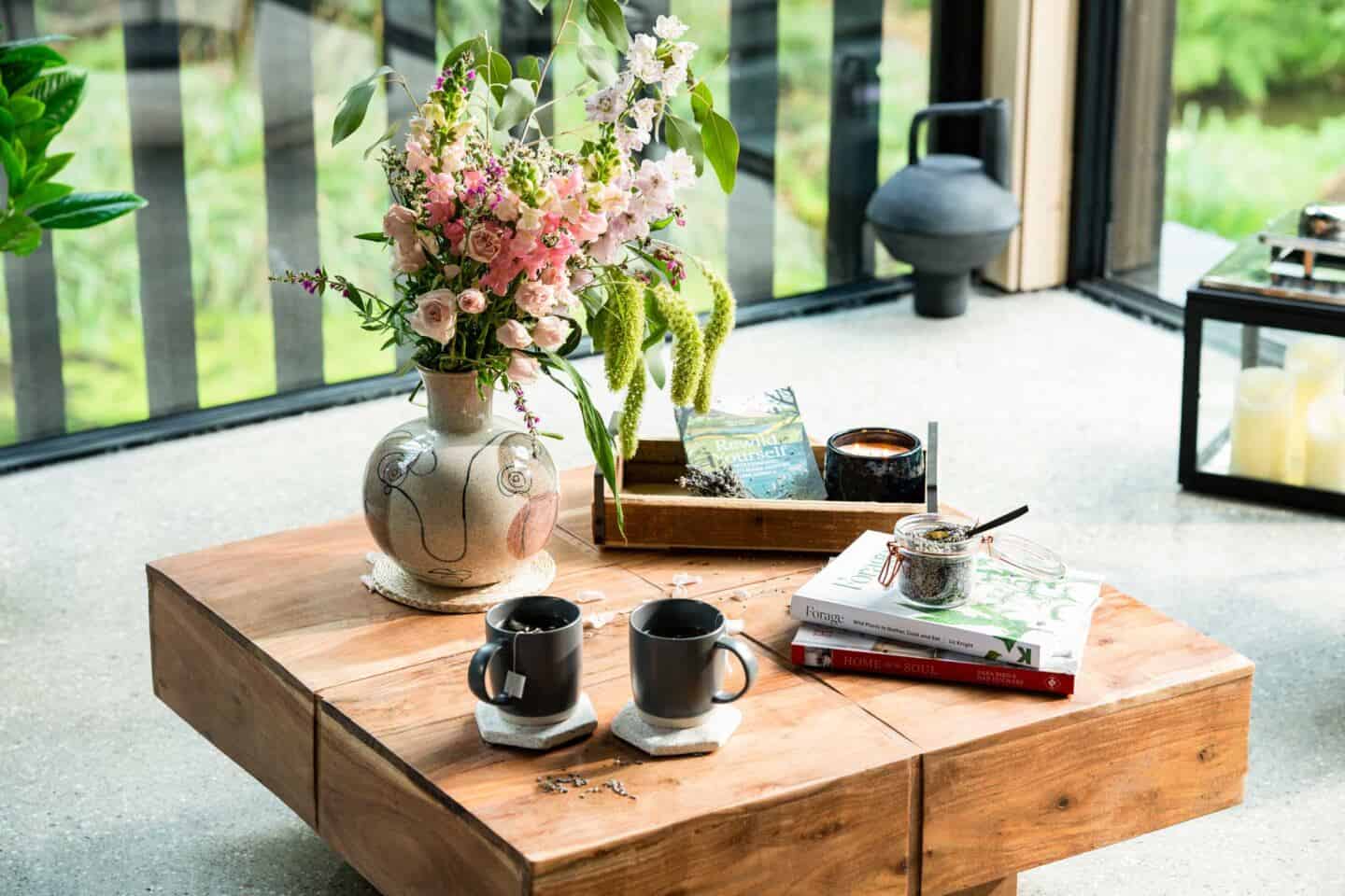 A coffee table from Wayfair and two mugs of tea next to a spring bunch of flowers at Wildwood Spa near Illfracombe in North Devon