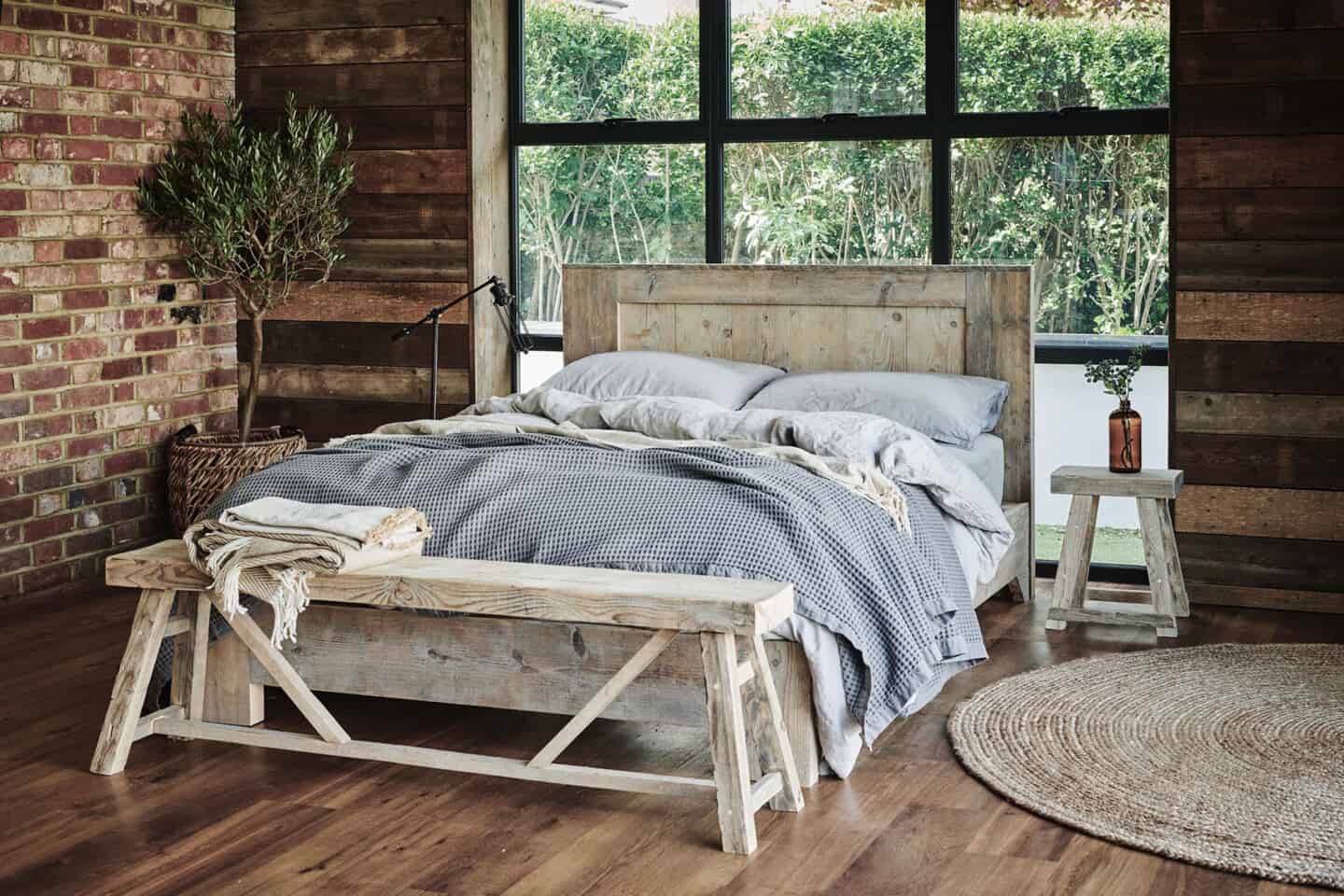 A double bed and two benches made from reclaimed wood which is a great material for sustainable interior design