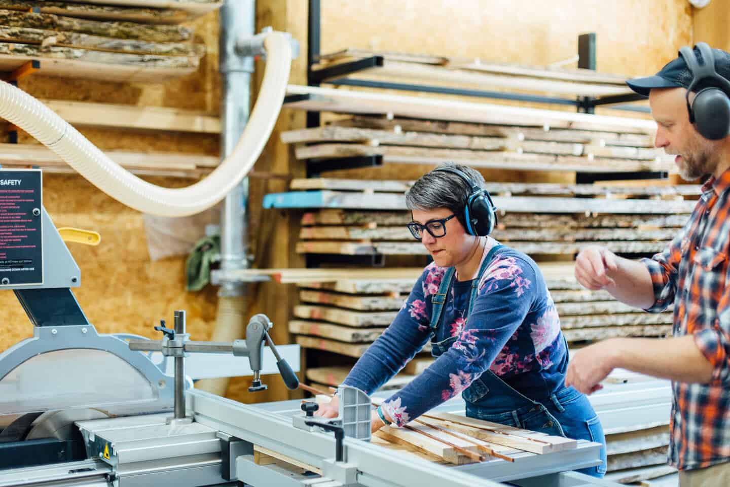 A woman uses a table saw instructed by the teacher on a woodwork course at The Woodlab in Devon