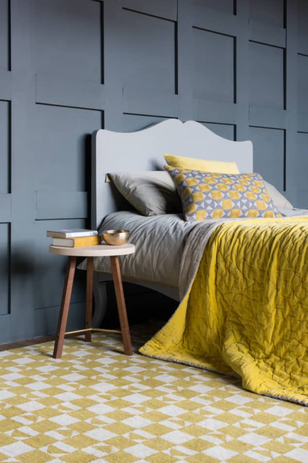 Grey bedroom featuring a yellow geometric rug and bedding from Niki Jones