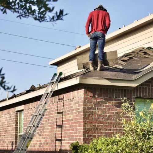 A man on a house roof fixing the tiles