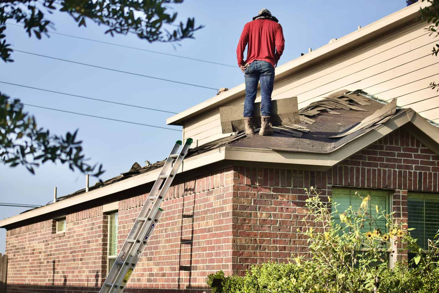 A man on a house roof fixing the tiles to prevent water damage